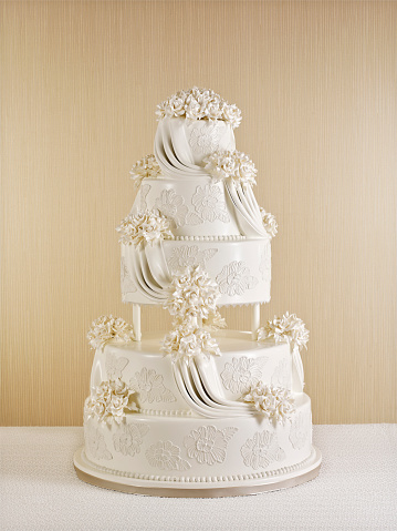 beige wedding cake with roses and ribbons close-up