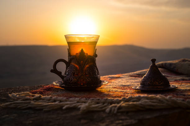 istock Arabian tea in glass on a eastern carpet. Eastern tea concept. Armudu traditional cup. Sunset background. Selective focus 1005086136