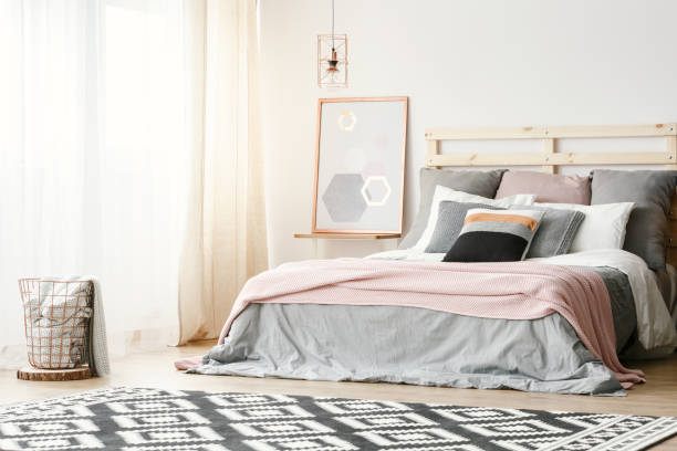 istock Pink blanket on grey bed in modern bedroom interior with poster and patterned carpet. Real photo 1005124654