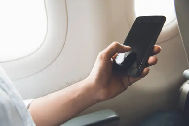 Photo of Male passenger turning off mobile phone on the airplane