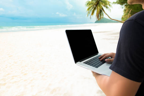 istock Independent man working with laptop computer online at the beach 1005124782