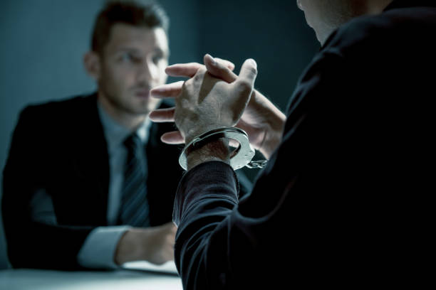 istock Criminal man with handcuffs being interviewed in interrogation room 1005124798