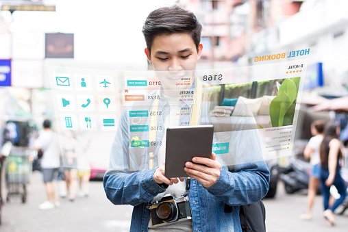 Asian tourist backpacker using mobile appication technology booking hotel online while traveling on vacations,  selective focus