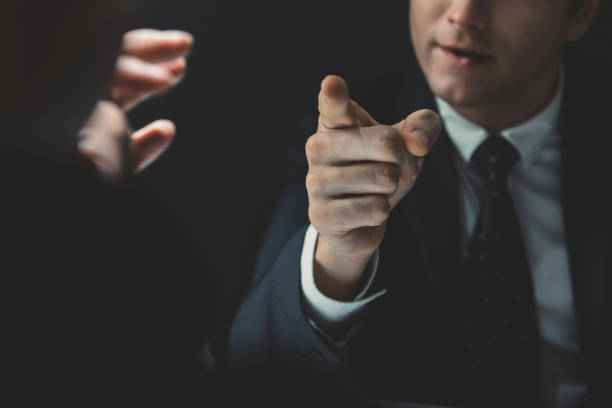 Angry man pointing hand to somesone he talking to Angry man in formal business suit pointing hand to somesone he talking to in dark interrogation room control point stock pictures, royalty-free photos & images