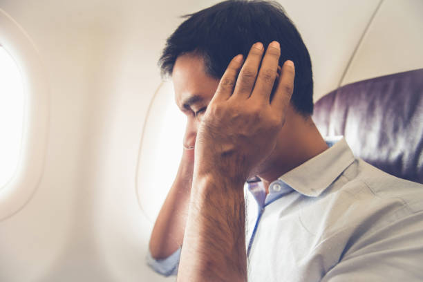 Male passenger having ear pop on the airplane Male passenger having ear pop on the airplane while taking off (or landing) landing touching down stock pictures, royalty-free photos & images