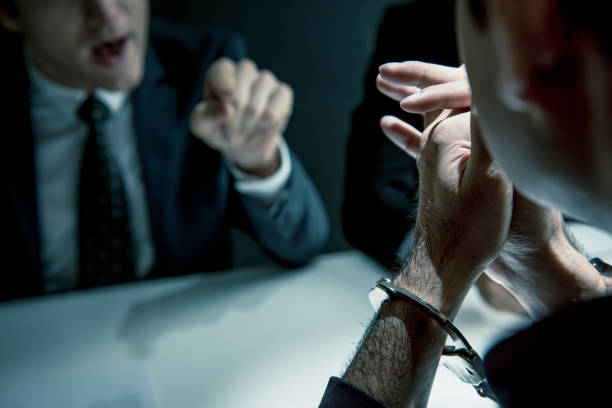 istock Criminal man with handcuffs being interviewed in interrogation room 1005124836