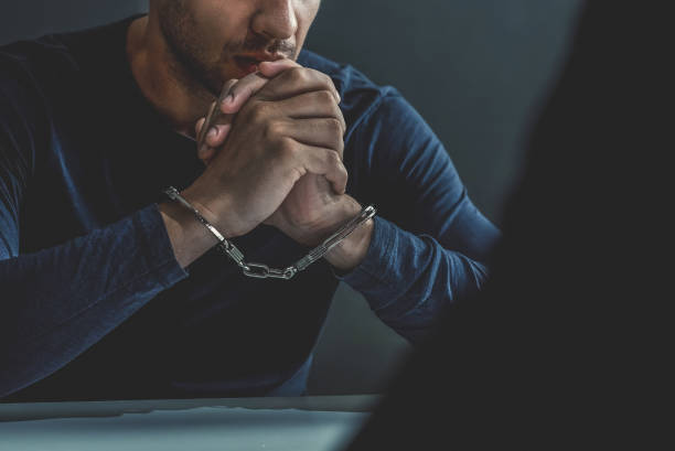 istock Criminal man with handcuffs in interrogation room 1005124868