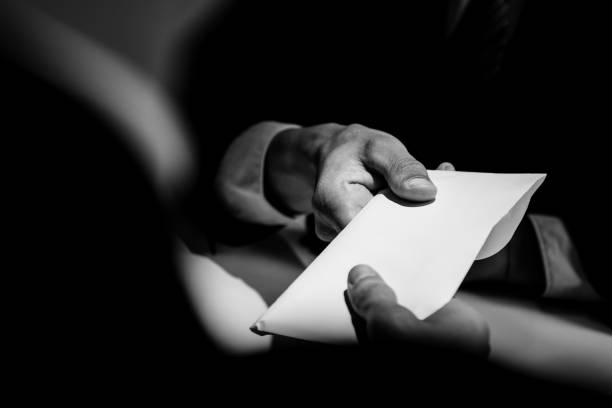 Businessman giving bribe money in the envelope to partner Businessman giving bribe money in the  envelope to partner in a corruption scam with black and white tone conspiracy stock pictures, royalty-free photos & images