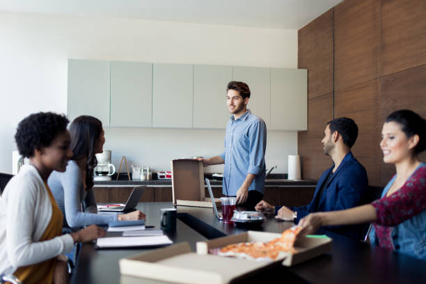 istock A small group of young people eating pizza at work 1005124960
