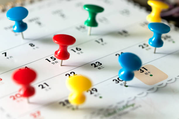 Thumb tack pins on calendar as reminder Various color thumb tack pins on calendar as reminder busy calendar stock pictures, royalty-free photos & images