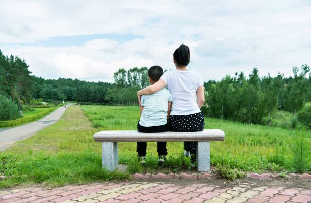 istock Mother and son sitting on park bench 1005170852