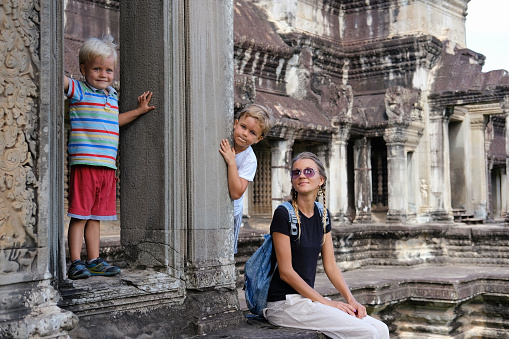 Happy tourists family, mother and two children in Angkor temple site, Cambodia. Concept travel, discovery