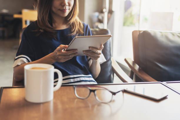 istock Young woman using smart phone in coffee shop drinking coffee 1005222422