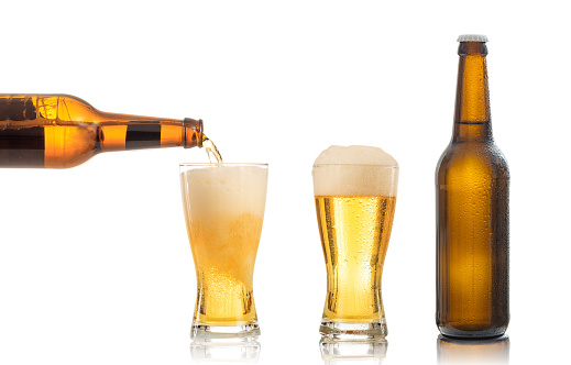 Bottles and glasses of beer on white background. Pouring beer into one glass