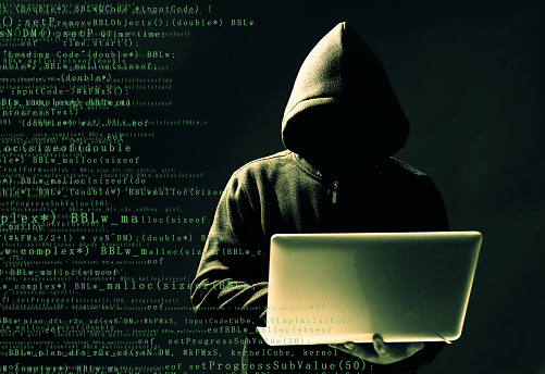 Computer hacker holding a laptop.