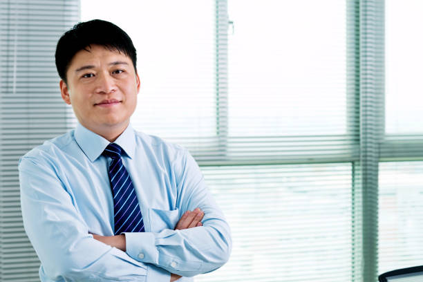 Businessman arms crossed standing in office.
