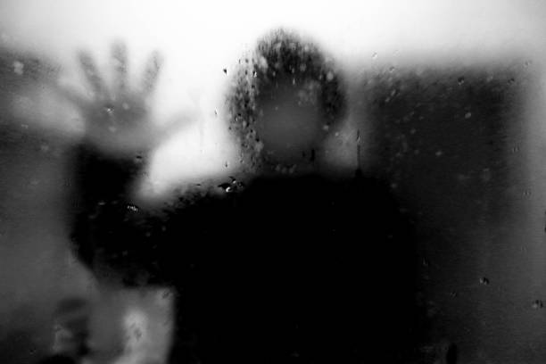 istock Dark room, mysterious man looking his reflection in a mirror. 1005259730