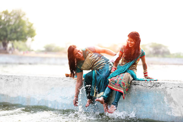 woman doing fun on vacations Two young friends doing full fun with lake water on vacations during sunset time outdoors. soaked suit stock pictures, royalty-free photos & images