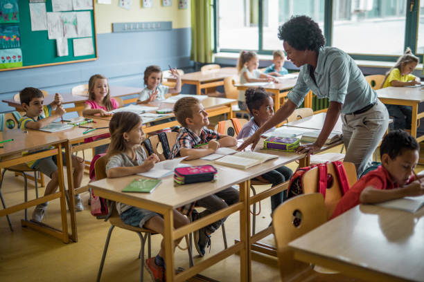 istock Happy black teacher talking to school kids on a class at elementary school. 1005282030