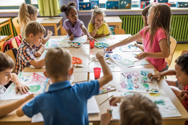 Large group of elementary students having an art class in the classroom. Group of students painting with water colors on art class at elementary school. art class photos stock pictures, royalty-free photos & images