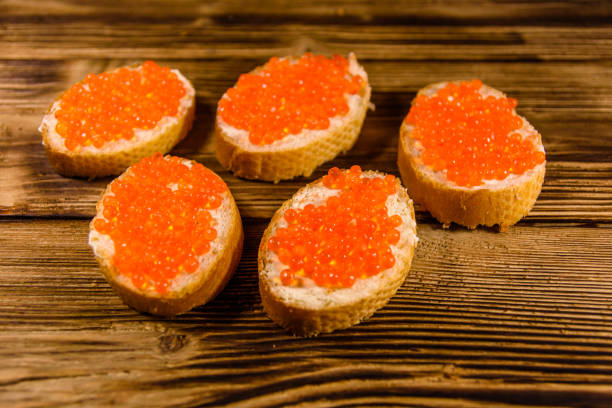 istock Sandwiches with red caviar on wooden table 1005306878
