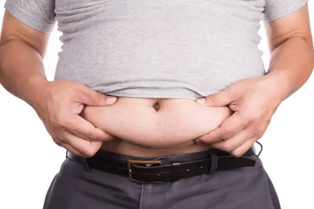 Photo of Close-up of man holding unhealthy big belly visceral subcutaneous fats