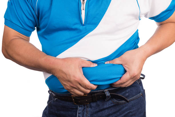 Man pinching unhealthy big belly with visceral or subcutaneous fats Man pinching own unhealthy big belly with visceral or subcutaneous fats. Pose health risk. visceral fat stock pictures, royalty-free photos & images