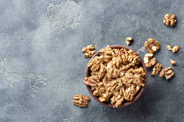 istock Walnut kernels on gray background with copy space. Nuts in clay bowl. Top view. 1005330886