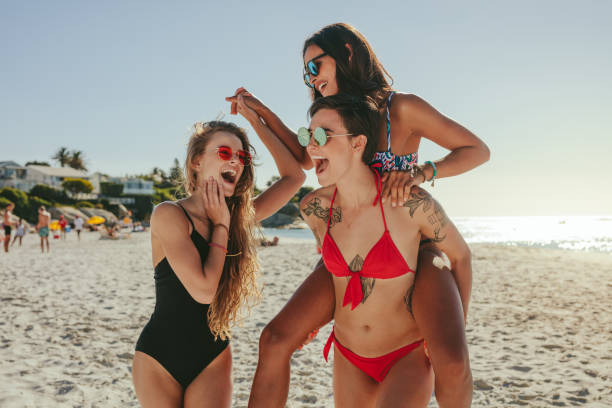 istock Girlfriends walking on beach in playful mood 1005331136