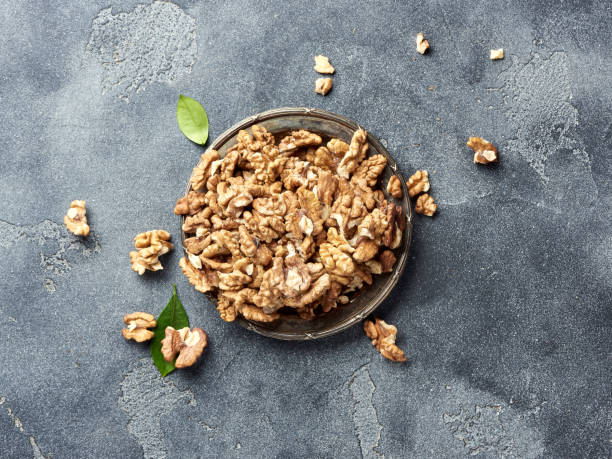 istock Walnut kernels on plate. Nuts with green leaves. Top view. 1005331314