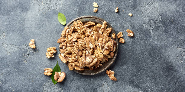 istock Walnut kernels on plate. Nuts on palate with green leaves. Top view. 1005331400