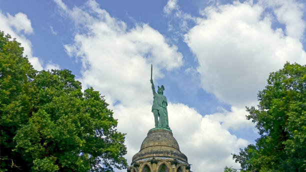 Huge Teutonic warrior Detmold, Germany - June 28, 2018: A huge bronze statue of a Teutonic warrior rises out of the Teutoburger forest holding his sword high up in the sky.  This Hermannsdenkmall or Hermann monument designed by Ernst von Bandel to remind us of this historical battle, became a national monument, but remained controversial as various groups failed to identify with the landmark. detmold stock pictures, royalty-free photos & images