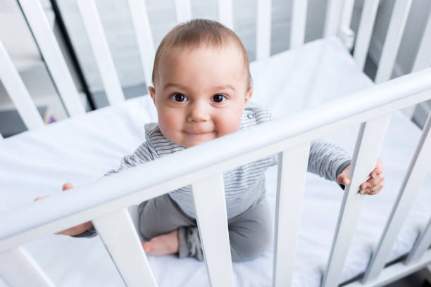 hoge hoekmening van schattig klein kind zitten in baby cot - babybox stockfoto's en -beelden