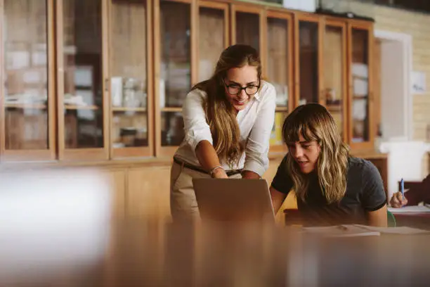 Photo of Teacher assisting the female student in study