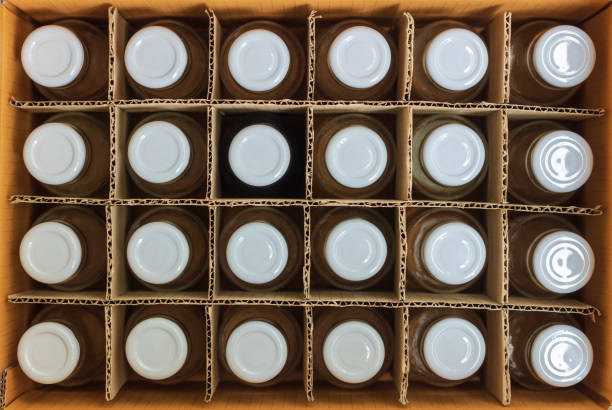 istock Glass bottles with white bottle caps in a cardboard box, Top view, Packaging concept. 1005345682
