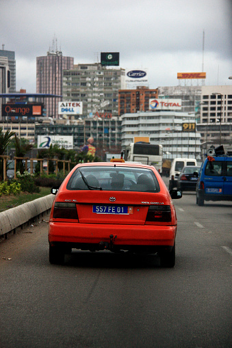 October 1st, 2012, Abidjan, Ivory Coast. A red Toyota car is driving along with the traffic flow towards the city center of Abidjan.