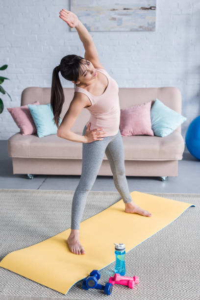 istock sporty young woman working out and doing side bend at home 1005353034