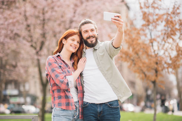 istock Young couple hugging and taking selfie at the park 1005353526