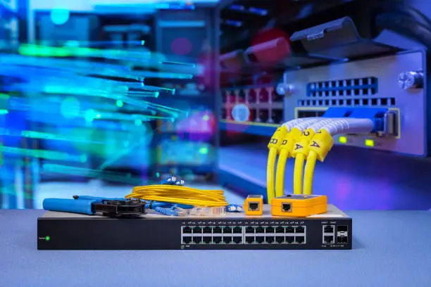 network gigabit switch and crimping pliers, tester network tool blending with  fiber optic cable and lighting of fiber optics on background in data center room
