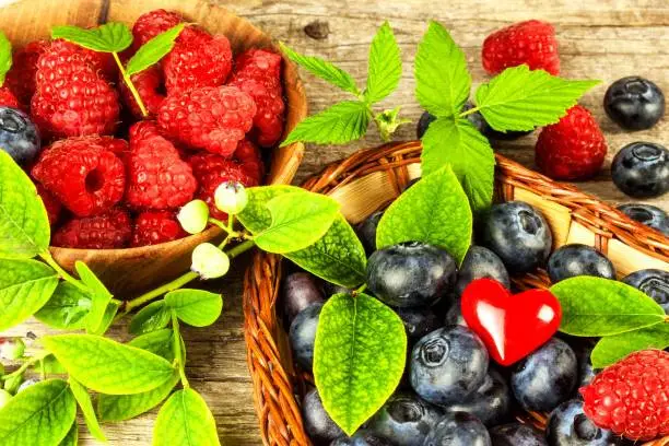 Fresh raspberries and blueberries on an old wooden table. Fruit picking. Healthy fruit. Sales of blueberries and raspberries