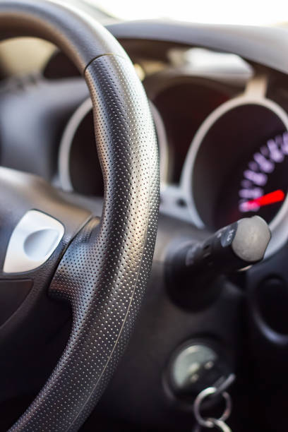 istock Close up modern black steering wheel, blurred dashboard, key and speedometer. Selective focus. Shallow depth of field. 1005378198