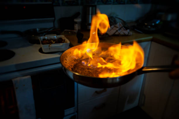 koch macht flambiertem in einer pfanne erhitzen, wodurch eine große flamme - ready to cook flash stock-fotos und bilder
