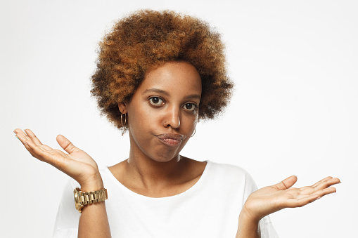 I don't know. Young afrcian american woman isolated on grey background, showing helpless gesture with arm and hands, as if he does not know what to do