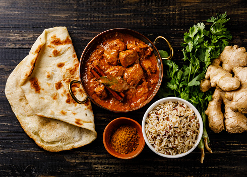 Chicken tikka masala spicy curry meat food with rice and naan bread on wooden background