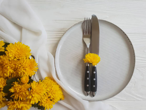 istock plate, fork, knife chrysanthemum flowers on a white wooden background 1005393818