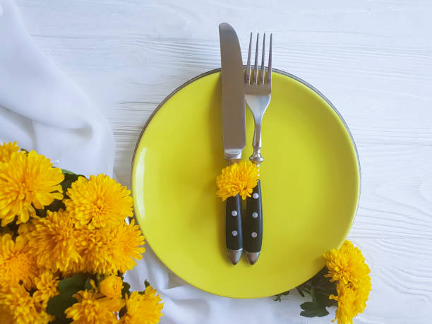 istock plate, fork, knife chrysanthemum flowers on a white wooden background 1005399404