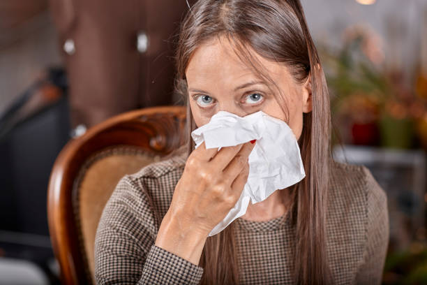 istock one woman sitting on brown chair while sneezing 1005402330