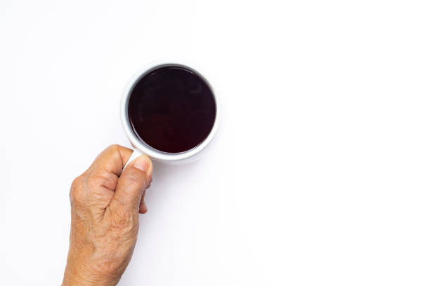 senior woman's left hand holding black coffee cup isolated on white background - copy space left imagens e fotografias de stock