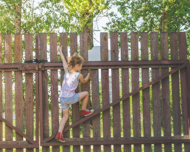 девушка поднимается забор в летний день - over the fence стоковые фото и изображения
