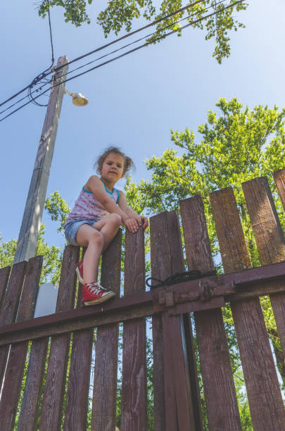 istock girl climbs the fence on a summer day 1005428746